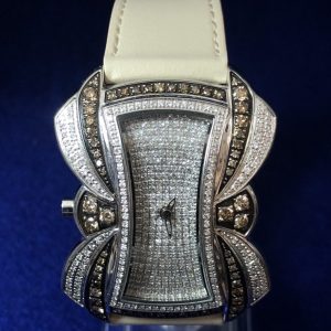 Reloj Joya en forma de lazo, modelo Cleopatra, cuajado de brillantes blancos y fancy brown, automático, con pulsera de piel genuina color hueso.