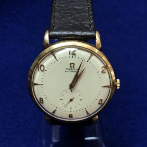 Reloj Omega vintage con cronógrafo, realizado en oro de ley 18 kts, automático con mecanismo de martillo, correa negra de piel genuina